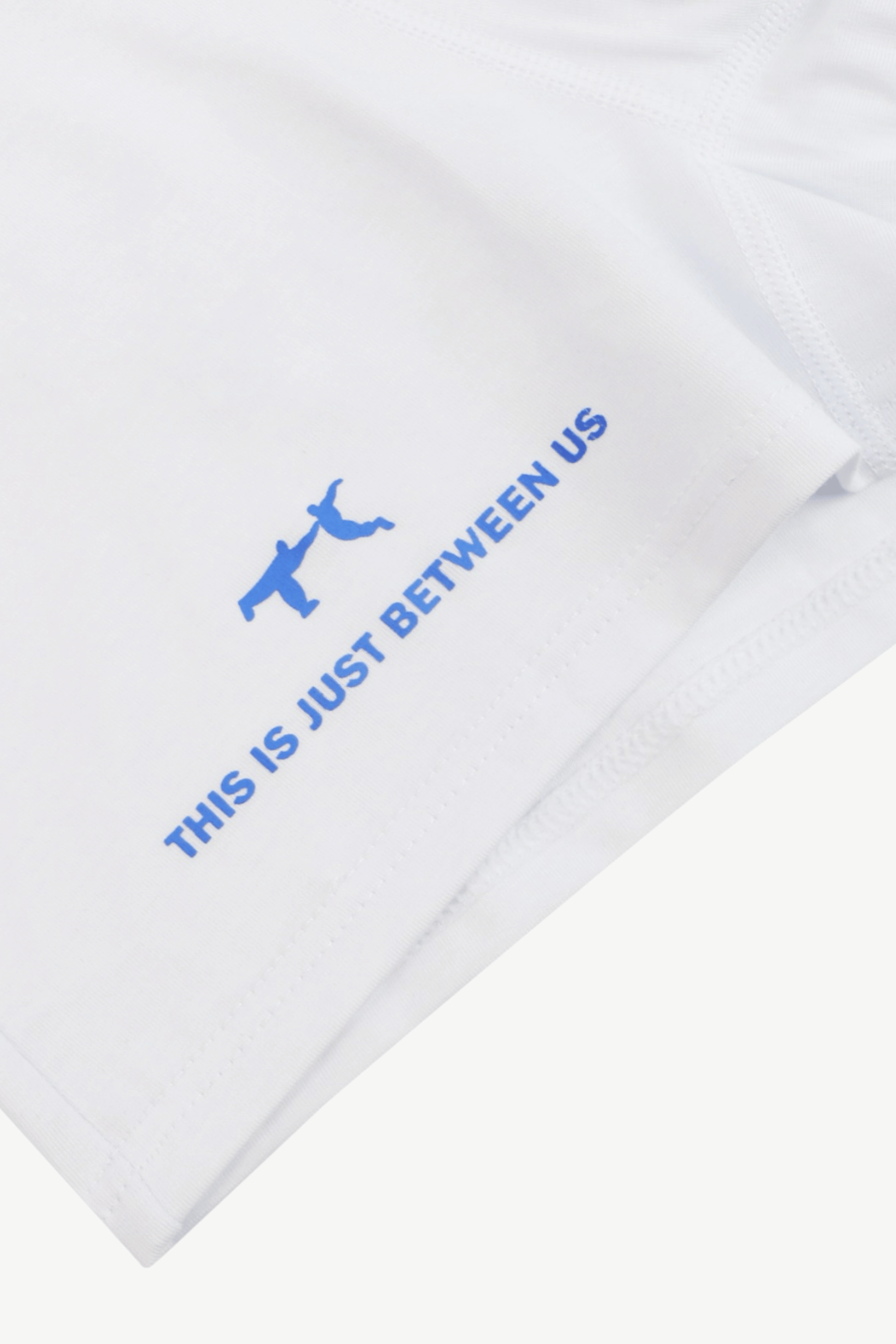 White shirt with blue text THIS IS JUST BETWEEN US and graphic on a white background. The Pressing Men's Underwear Boxer Brief White Logo Detail THIS IS JUST BETWEEN US Organic Cotton-Modal, No Polyester — TACTO Collective