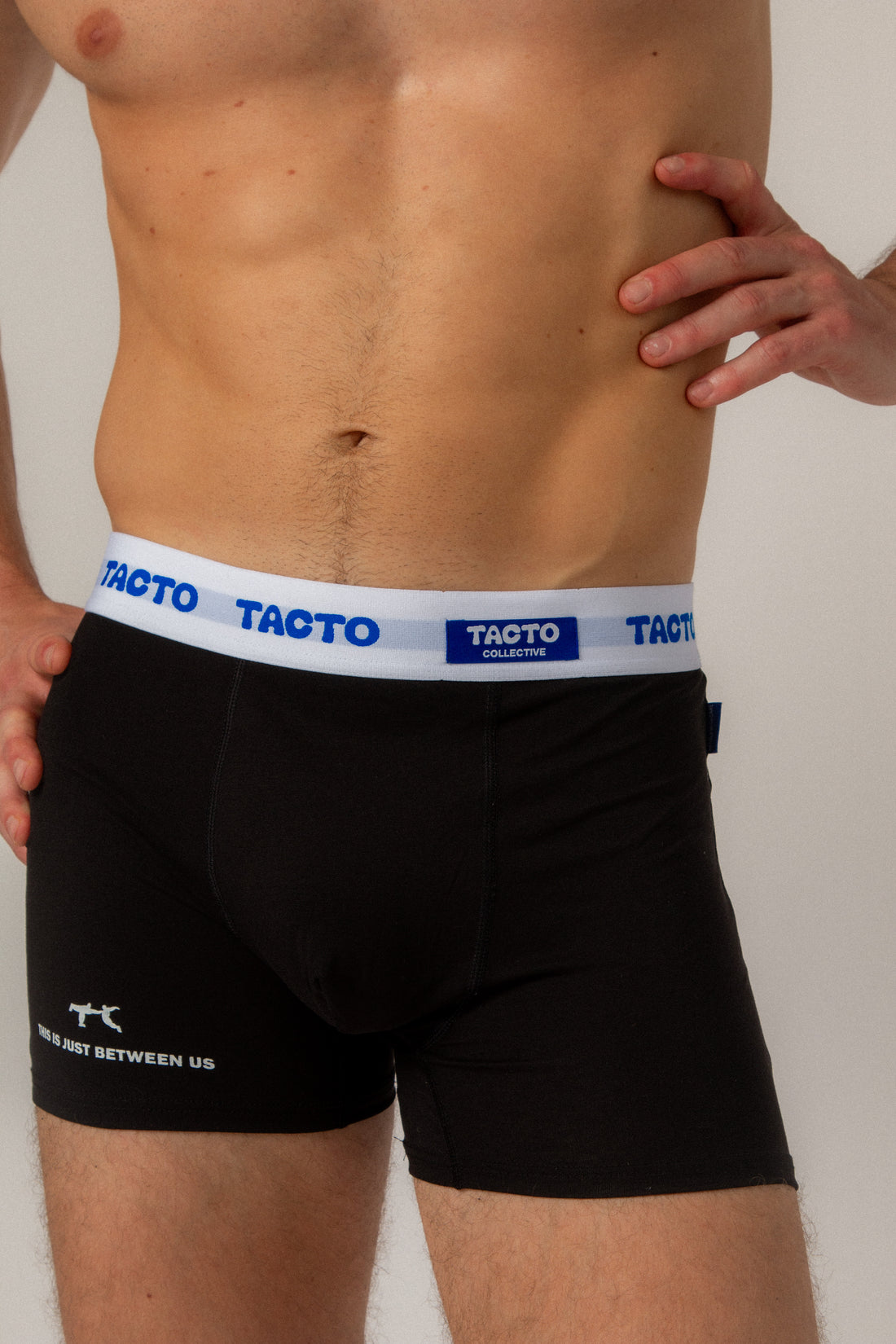 Person wearing black boxer briefs with Tacto waistband on a plain background