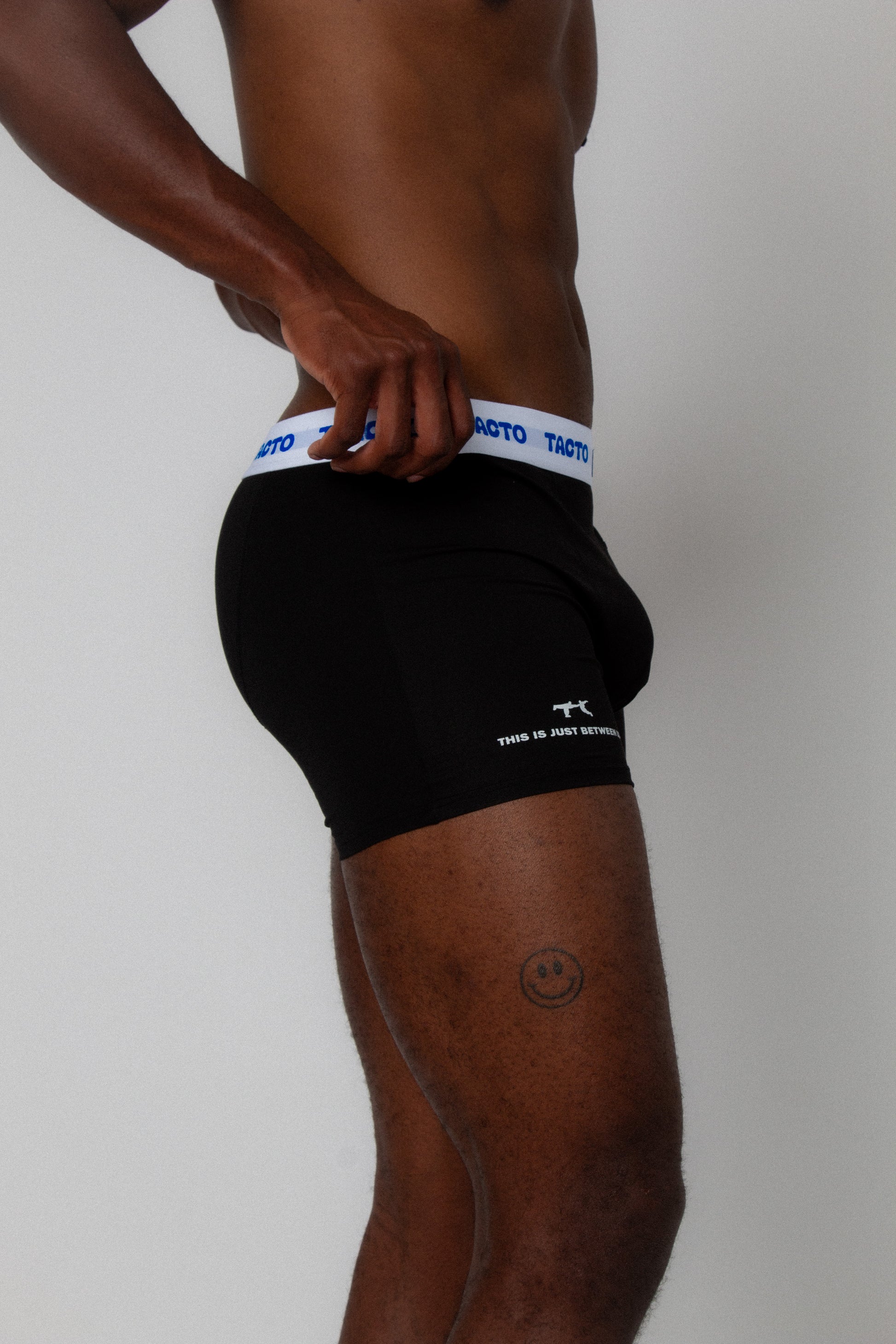 Person wearing black boxer briefs with a white waistband on a plain background