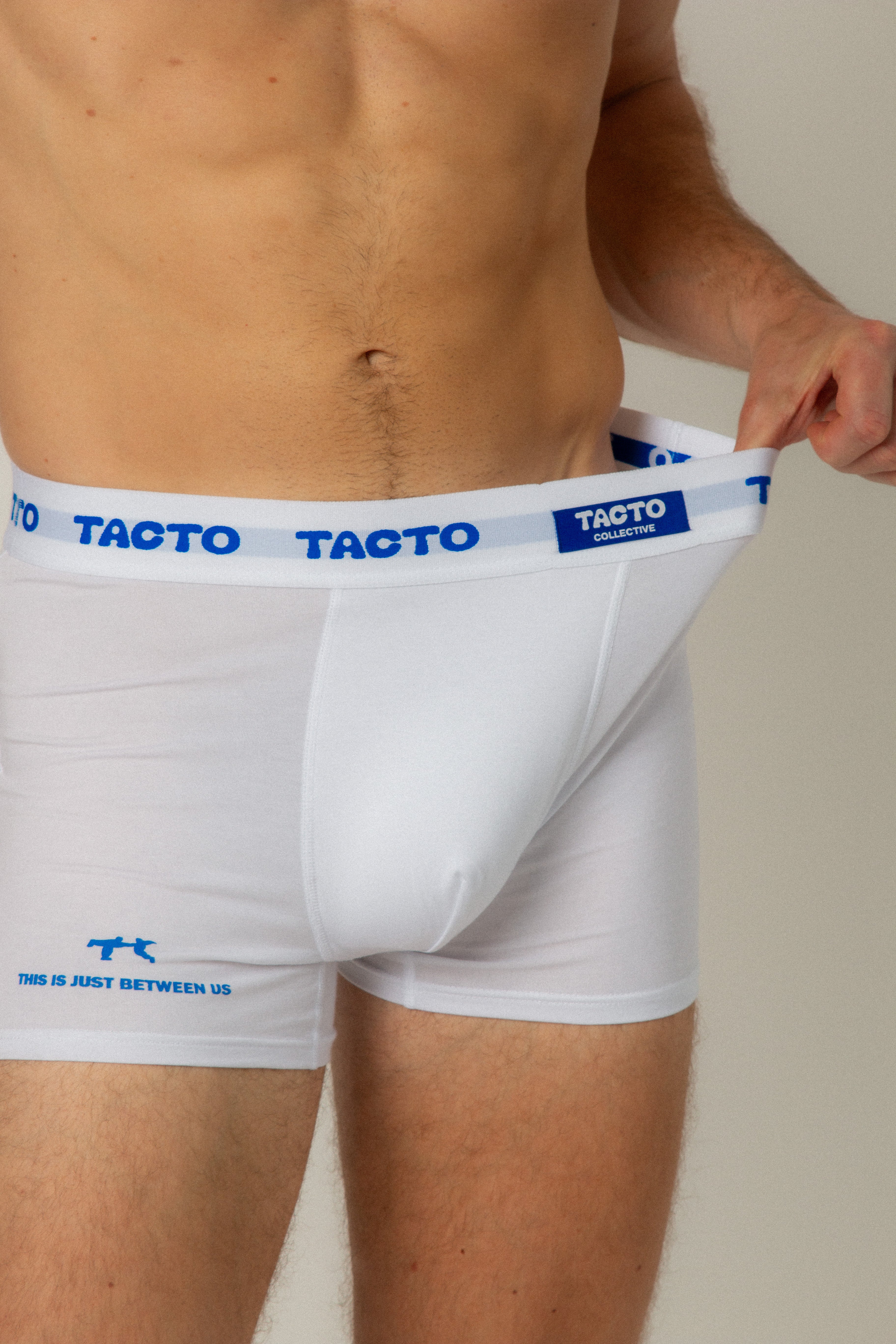 White boxer briefs with blue branding on a plain background. Tacto Collective. Stretching  waistband